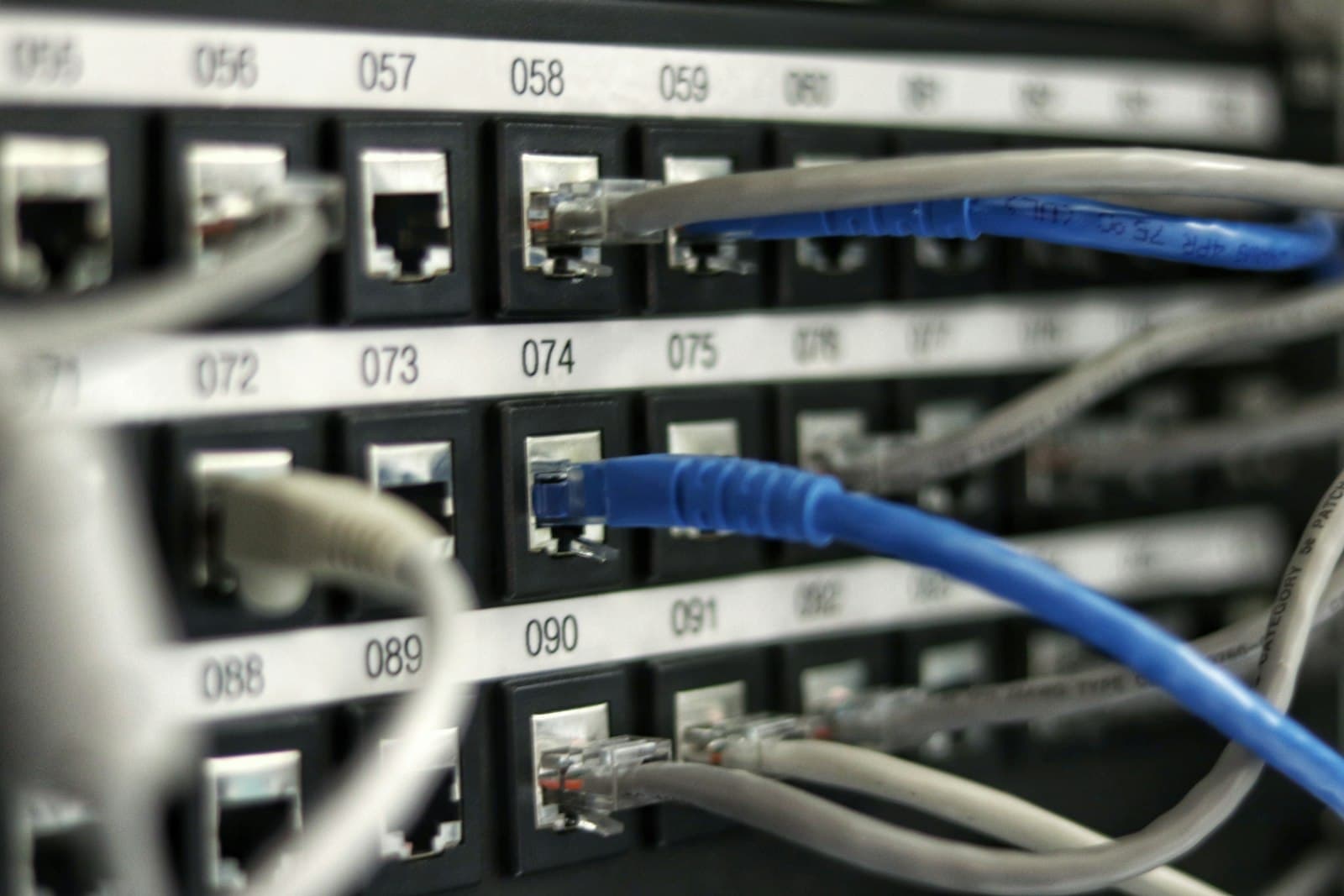 Câbles ethernet RJ45 colorés branchés sur switch réseau résidentiel